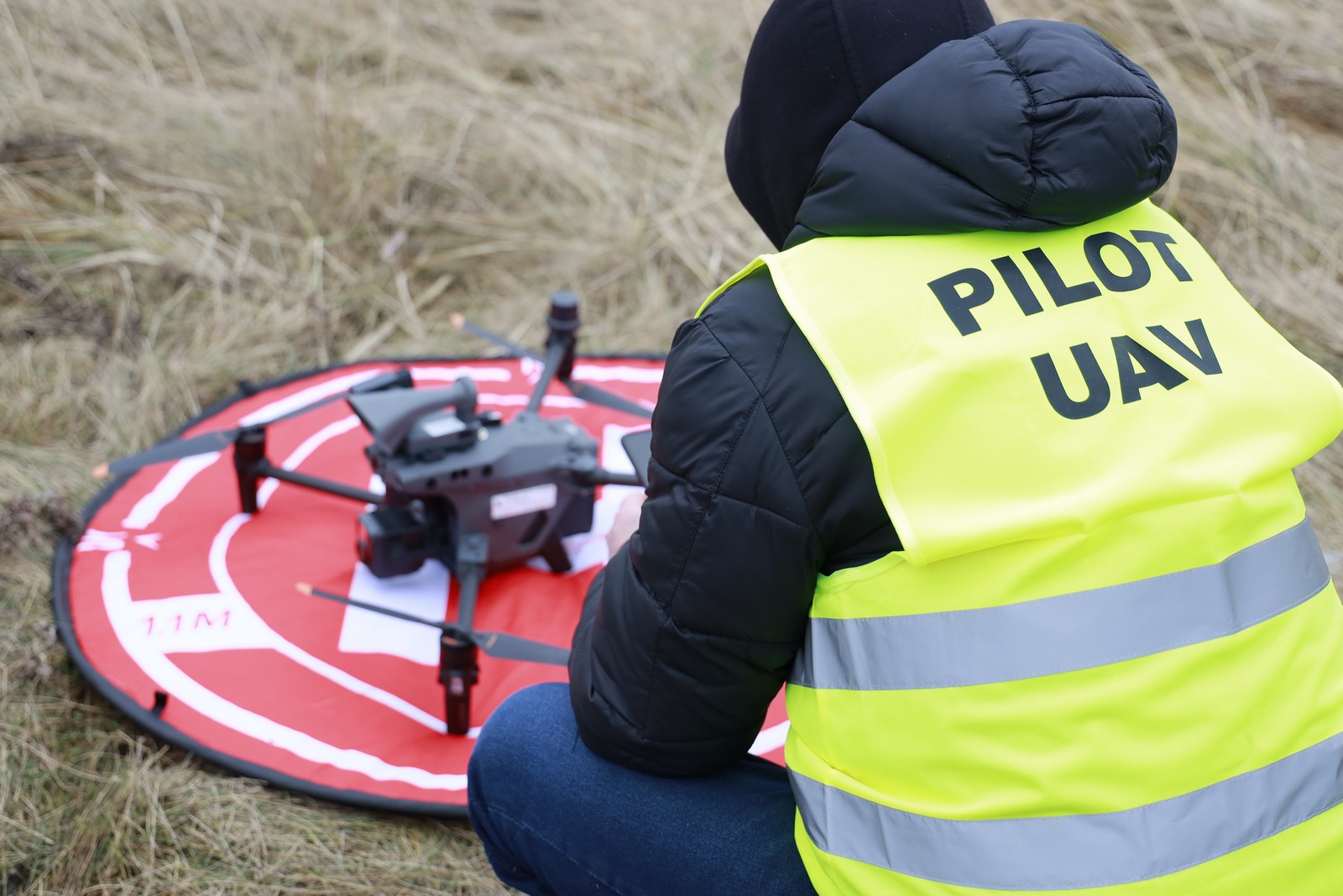 Na zdjęciu znajduje się pilot drona przygotowujący się do lotu dronem
